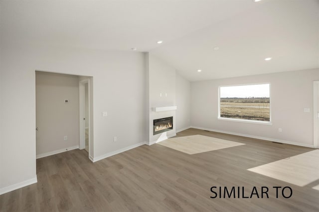 6565 NE 11th Ct, Des Moines, IA 50313 - unfurnished living room with wood finished floors, vaulted ceiling, a glass covered fireplace, baseboards, and recessed lighting