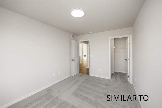 6557 NE 11th Ct, Des Moines, IA 50313 - unfurnished bedroom featuring carpet flooring, a spacious closet, and a closet