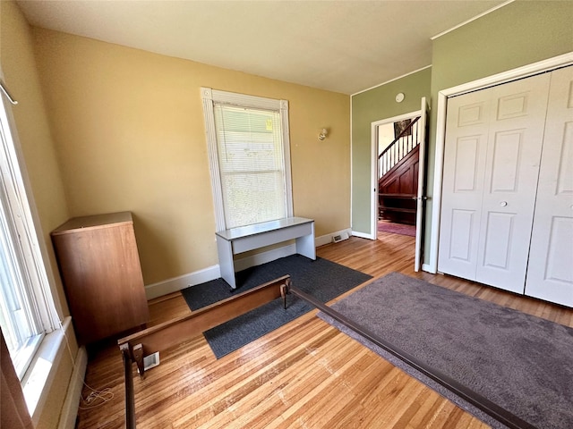 unfurnished bedroom featuring wood finished floors, baseboards, and a closet