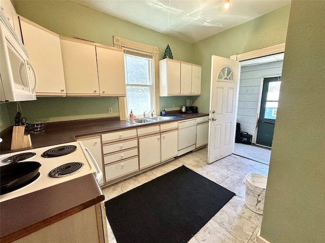 kitchen with white appliances, plenty of natural light, dark countertops, and a sink