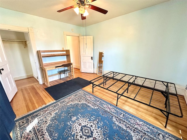 bedroom featuring wood finished floors, baseboards, a closet, and ceiling fan
