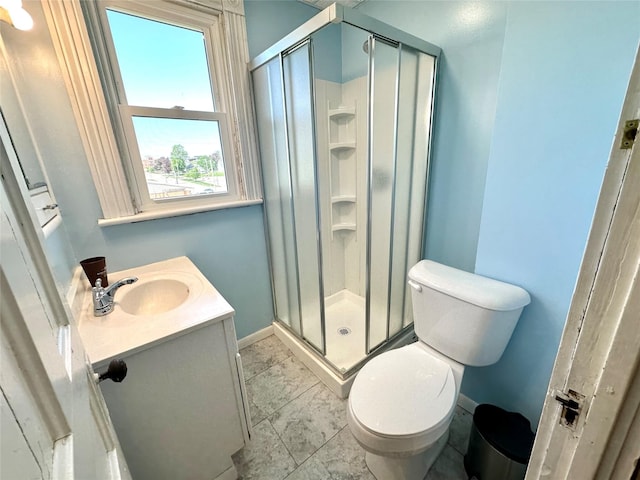 bathroom featuring a stall shower, marble look tiles, toilet, vanity, and baseboards