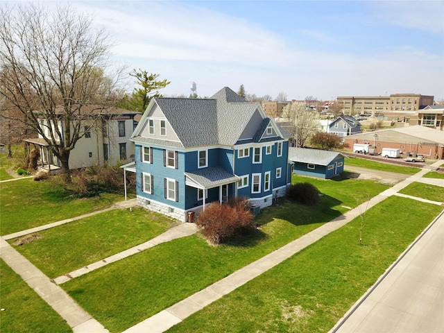 view of front of house featuring roof with shingles, a front lawn, a residential view, and driveway