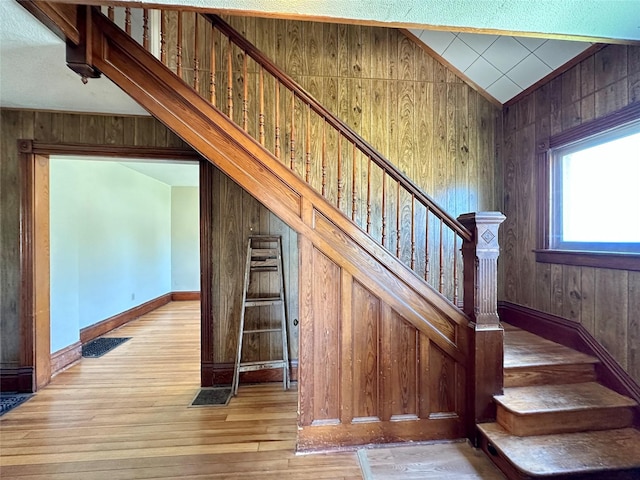 stairs featuring wood walls, hardwood / wood-style floors, and baseboards