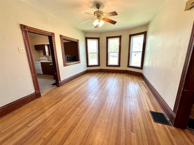 empty room featuring a ceiling fan, light wood-style floors, and baseboards