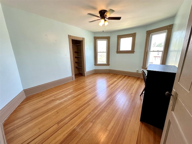 unfurnished room with healthy amount of natural light, light wood-type flooring, baseboards, and ceiling fan