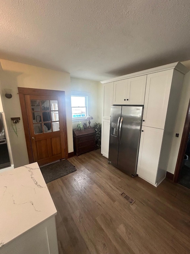 1913 N 1st St, Winterset, IA 50273 - kitchen with stainless steel fridge with ice dispenser, a textured ceiling, dark wood-style flooring, white cabinets, and light stone counters