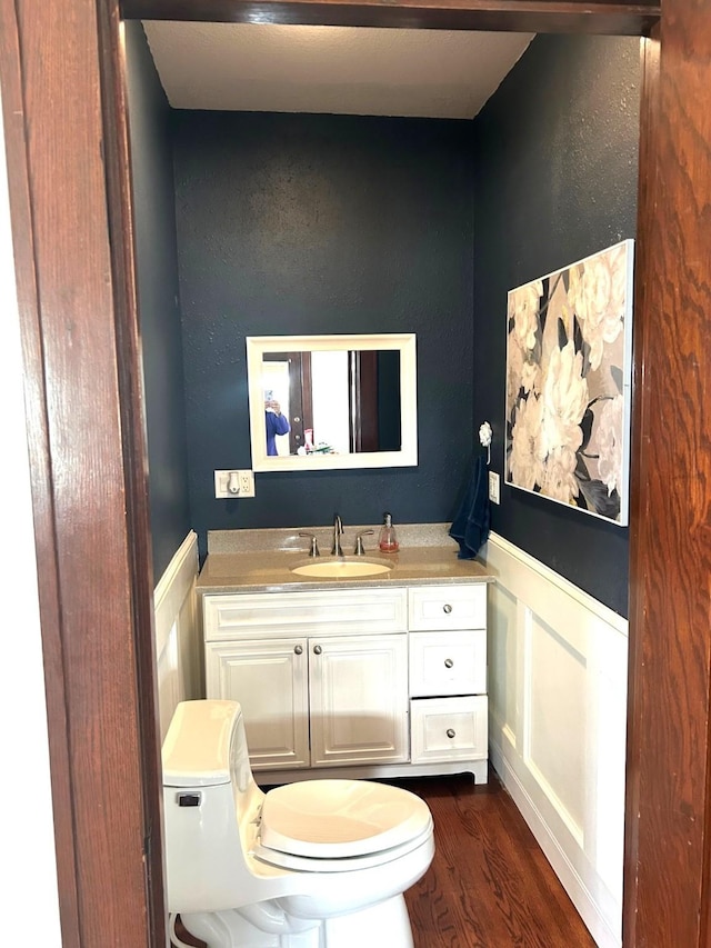 1913 N 1st St, Winterset, IA 50273 - bathroom with toilet, wainscoting, vanity, and wood finished floors