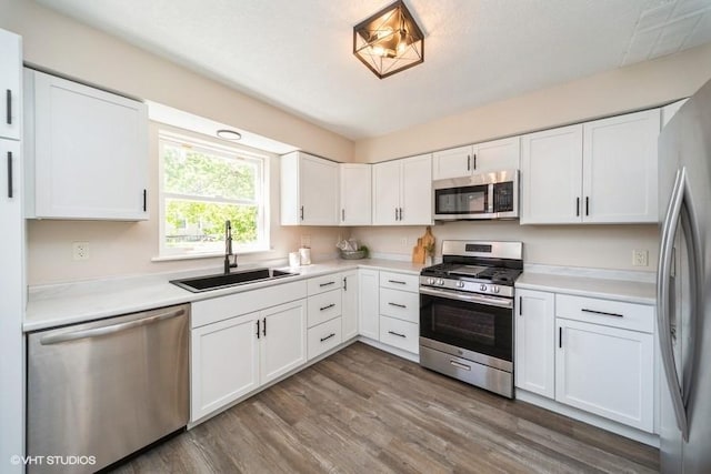 930 Forest Ave, Des Moines, IA 50314 - kitchen featuring appliances with stainless steel finishes, a sink, wood finished floors, white cabinets, and light countertops