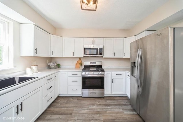 930 Forest Ave, Des Moines, IA 50314 - kitchen with appliances with stainless steel finishes, white cabinets, light countertops, and wood finished floors