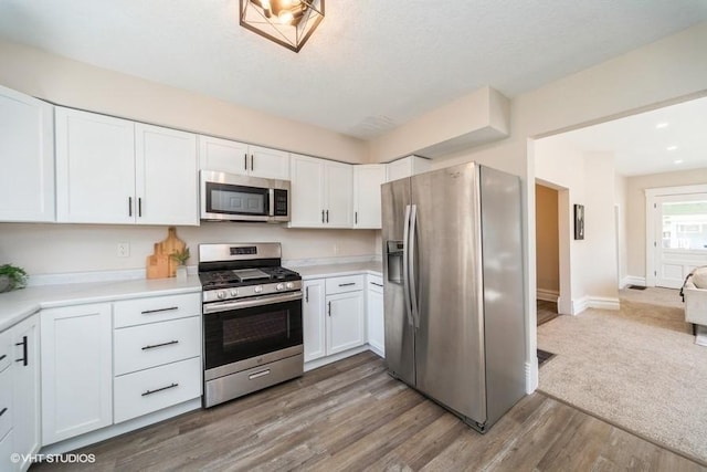 930 Forest Ave, Des Moines, IA 50314 - kitchen with appliances with stainless steel finishes, white cabinetry, light countertops, wood finished floors, and baseboards
