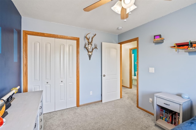 bedroom with light colored carpet, a closet, baseboards, and a ceiling fan