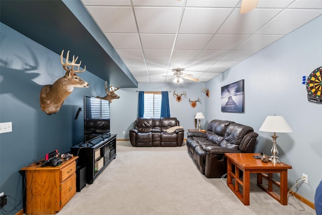 carpeted living area featuring a drop ceiling, a ceiling fan, and baseboards