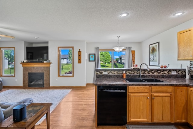 kitchen with dishwasher, a sink, a textured ceiling, a peninsula, and open floor plan
