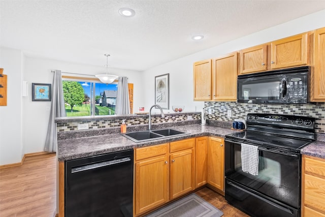 kitchen featuring black appliances, a sink, a peninsula, tasteful backsplash, and recessed lighting