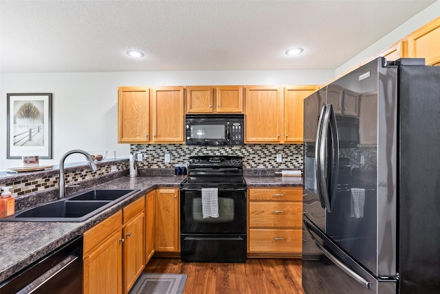 kitchen with black appliances, a sink, dark wood-style flooring, backsplash, and recessed lighting