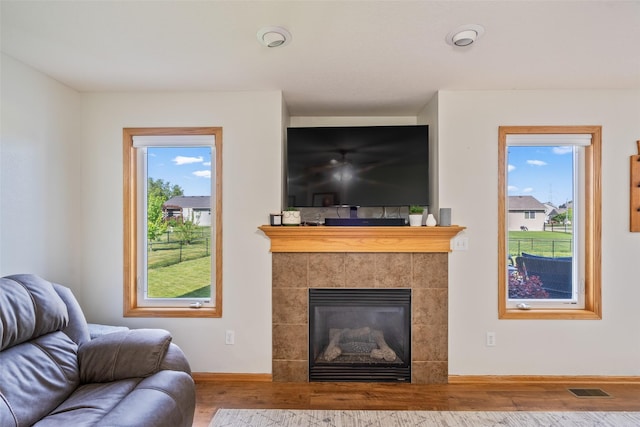 living room featuring wood finished floors, baseboards, and a tile fireplace