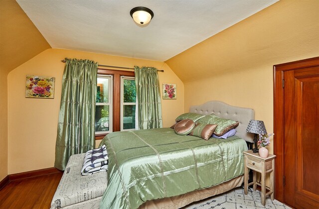bedroom with lofted ceiling, baseboards, and wood finished floors