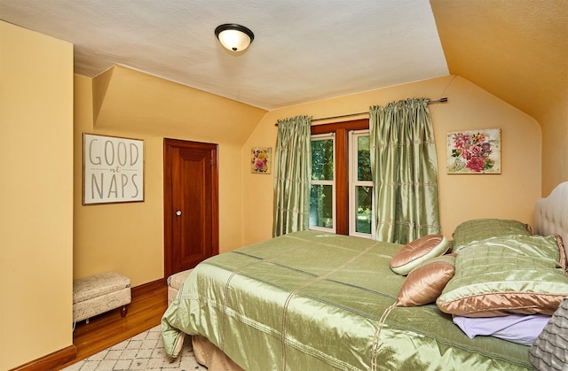 bedroom featuring wood finished floors and lofted ceiling