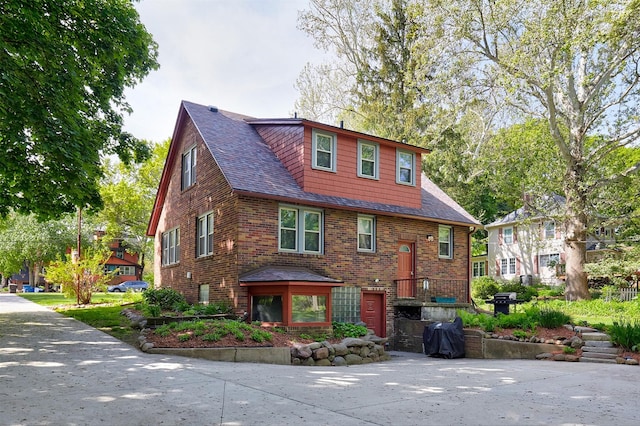view of front of house featuring brick siding and a shingled roof