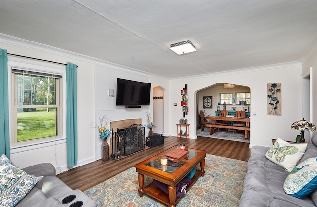 living room with arched walkways, ornamental molding, wood finished floors, and baseboards