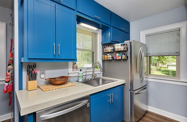kitchen featuring stainless steel dishwasher, blue cabinets, a sink, and light countertops