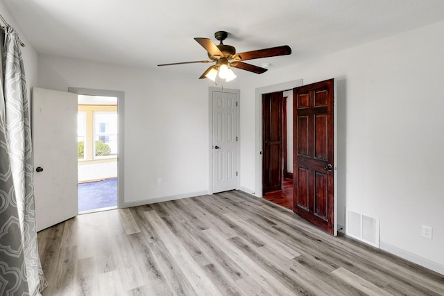 325 E Maple Ave, Ottumwa, IA 52501 - unfurnished bedroom with light wood finished floors, baseboards, and a ceiling fan