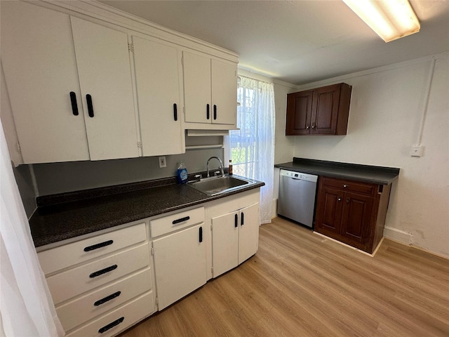 kitchen featuring stainless steel dishwasher, a sink, dark countertops, light wood-style floors, and white cabinets