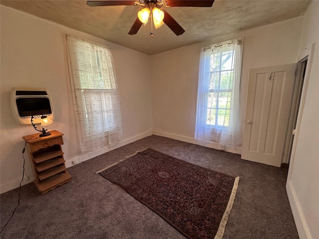 carpeted spare room with heating unit, a ceiling fan, and baseboards