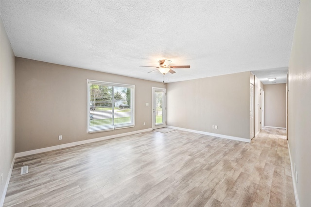 spare room featuring light wood-style flooring, ceiling fan, a textured ceiling, and baseboards