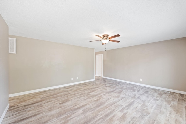 empty room with light wood-type flooring, ceiling fan, baseboards, and a textured ceiling