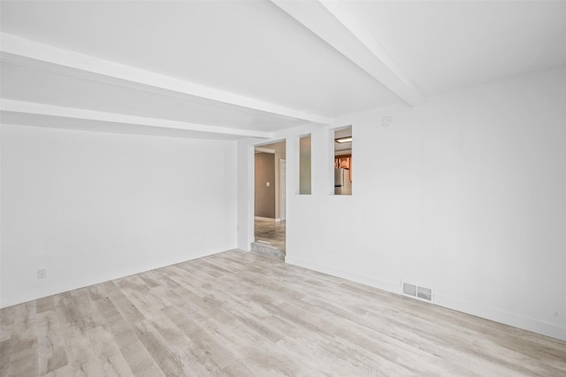 spare room featuring beamed ceiling and wood finished floors