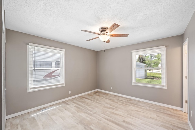 spare room featuring ceiling fan, light wood-type flooring, a textured ceiling, and baseboards