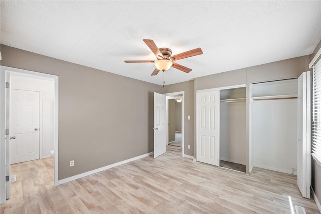 unfurnished bedroom with light wood finished floors, baseboards, a ceiling fan, and two closets
