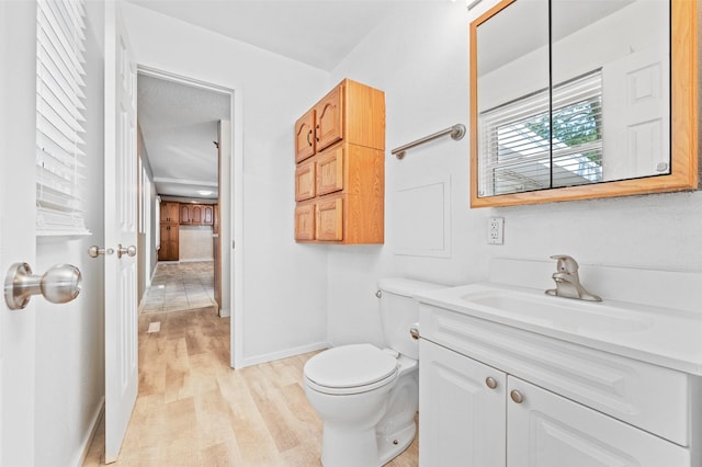 bathroom featuring wood finished floors, toilet, vanity, and baseboards