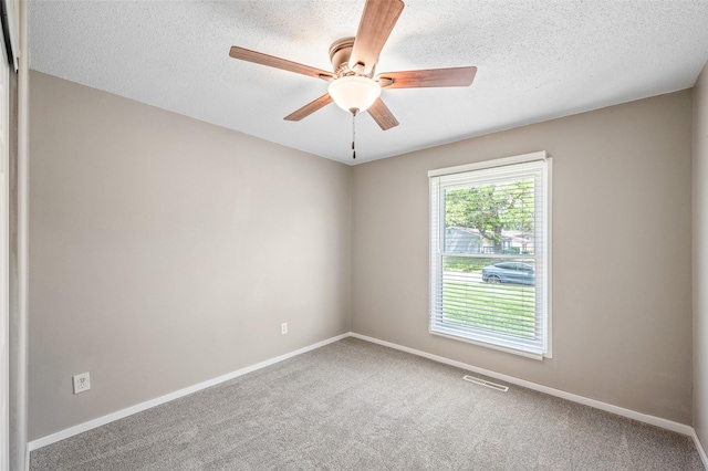 carpeted spare room with ceiling fan, baseboards, and a textured ceiling
