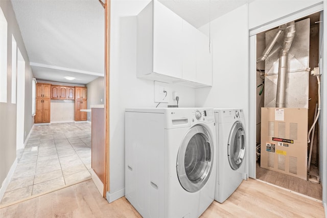 laundry area featuring separate washer and dryer, baseboards, light wood-type flooring, cabinet space, and heating unit