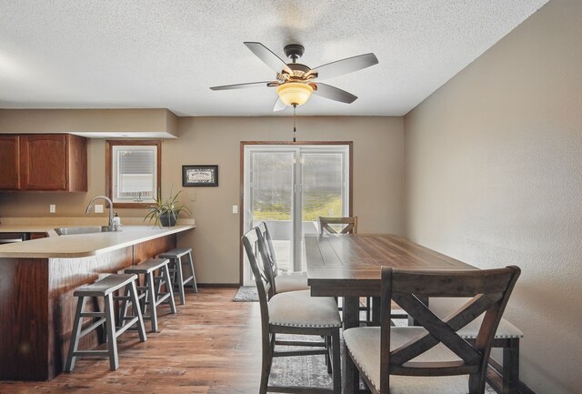 7052 Plum Dr, Urbandale, IA 50322 - dining area featuring ceiling fan, light wood-style flooring, a textured ceiling, and baseboards