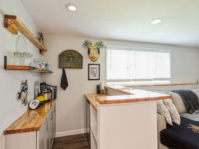 5031 Cherrywood Dr, West Des Moines, IA 50265 - kitchen with wooden counters, dark wood finished floors, a peninsula, baseboards, and white cabinetry