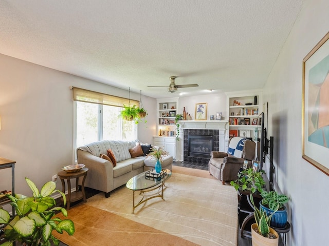 5031 Cherrywood Dr, West Des Moines, IA 50265 - living room with a textured ceiling, a tiled fireplace, a ceiling fan, and built in shelves