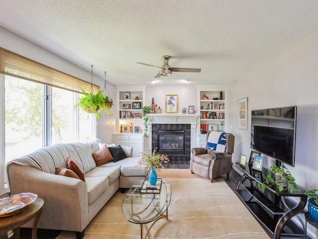 5031 Cherrywood Dr, West Des Moines, IA 50265 - living room featuring a tiled fireplace, a textured ceiling, ceiling fan, and built in features