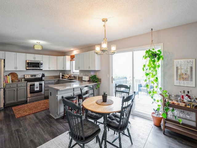 5031 Cherrywood Dr, West Des Moines, IA 50265 - kitchen featuring appliances with stainless steel finishes, a chandelier, a sink, a peninsula, and dark wood-type flooring