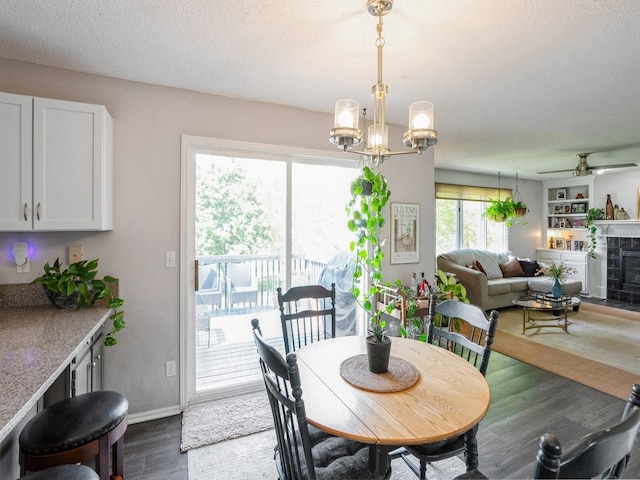 5031 Cherrywood Dr, West Des Moines, IA 50265 - dining room featuring dark wood-style flooring, a tile fireplace, a chandelier, a textured ceiling, and a ceiling fan