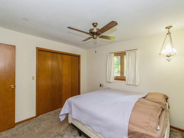 carpeted bedroom featuring a closet, baseboards, and a ceiling fan