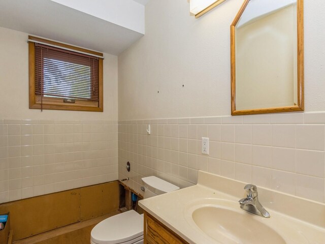 bathroom with tile walls, toilet, vanity, and wainscoting