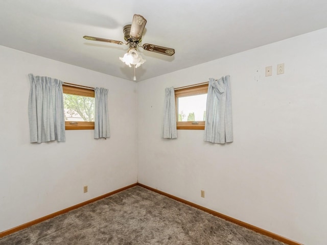 carpeted spare room featuring baseboards and a ceiling fan