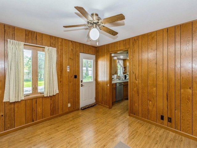 doorway to outside with wood finished floors, a ceiling fan, a sink, wood walls, and baseboards