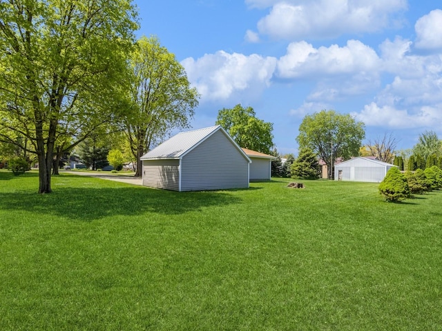 view of green lawn with an outdoor structure and a detached garage
