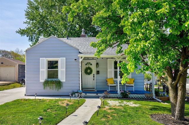 bungalow-style home with covered porch, a front yard, an outdoor structure, and roof with shingles