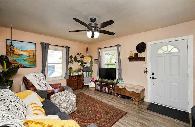 living area featuring healthy amount of natural light, a ceiling fan, and wood finished floors
